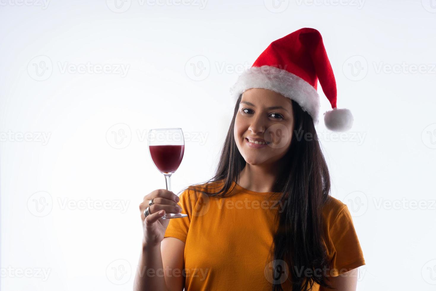 mujer joven y bonita con un sombrero de santa claus, sosteniendo una copa de vino. Fondo blanco foto