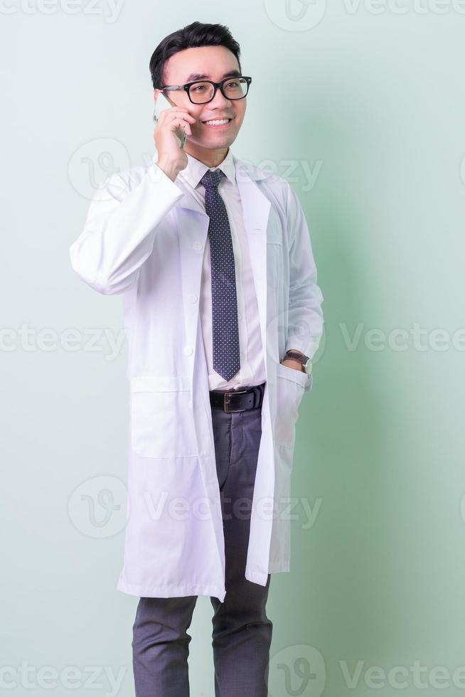 Asian doctor standing on green background photo