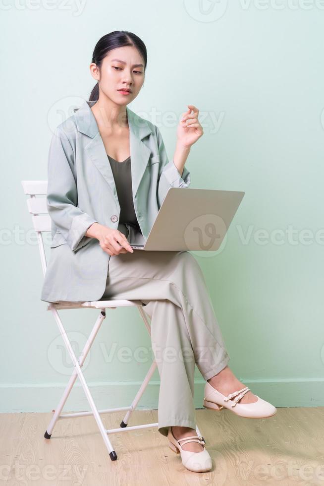 Young Asian businesswoman sitting on chair on green background photo