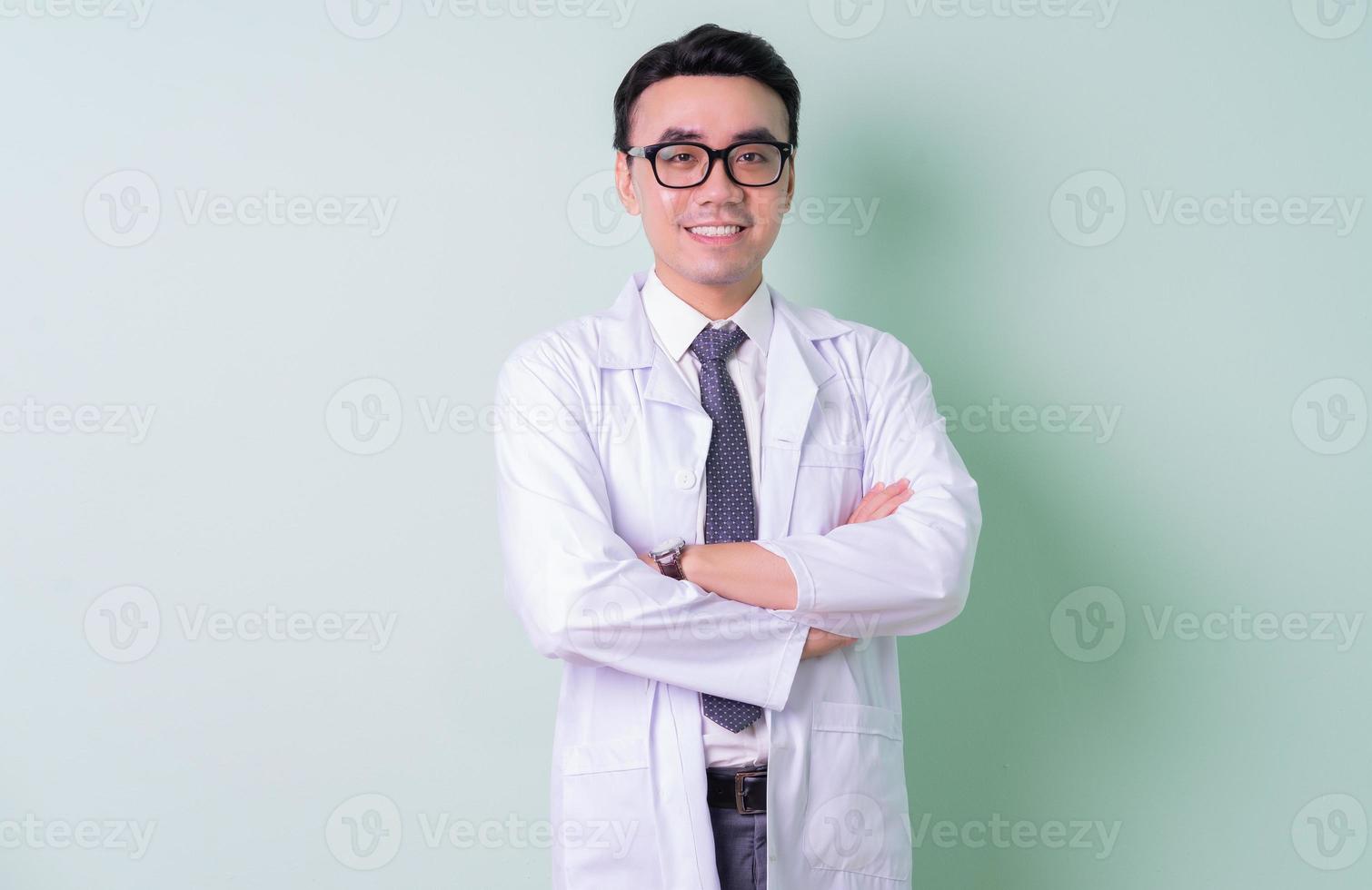 Asian doctor standing on green background photo