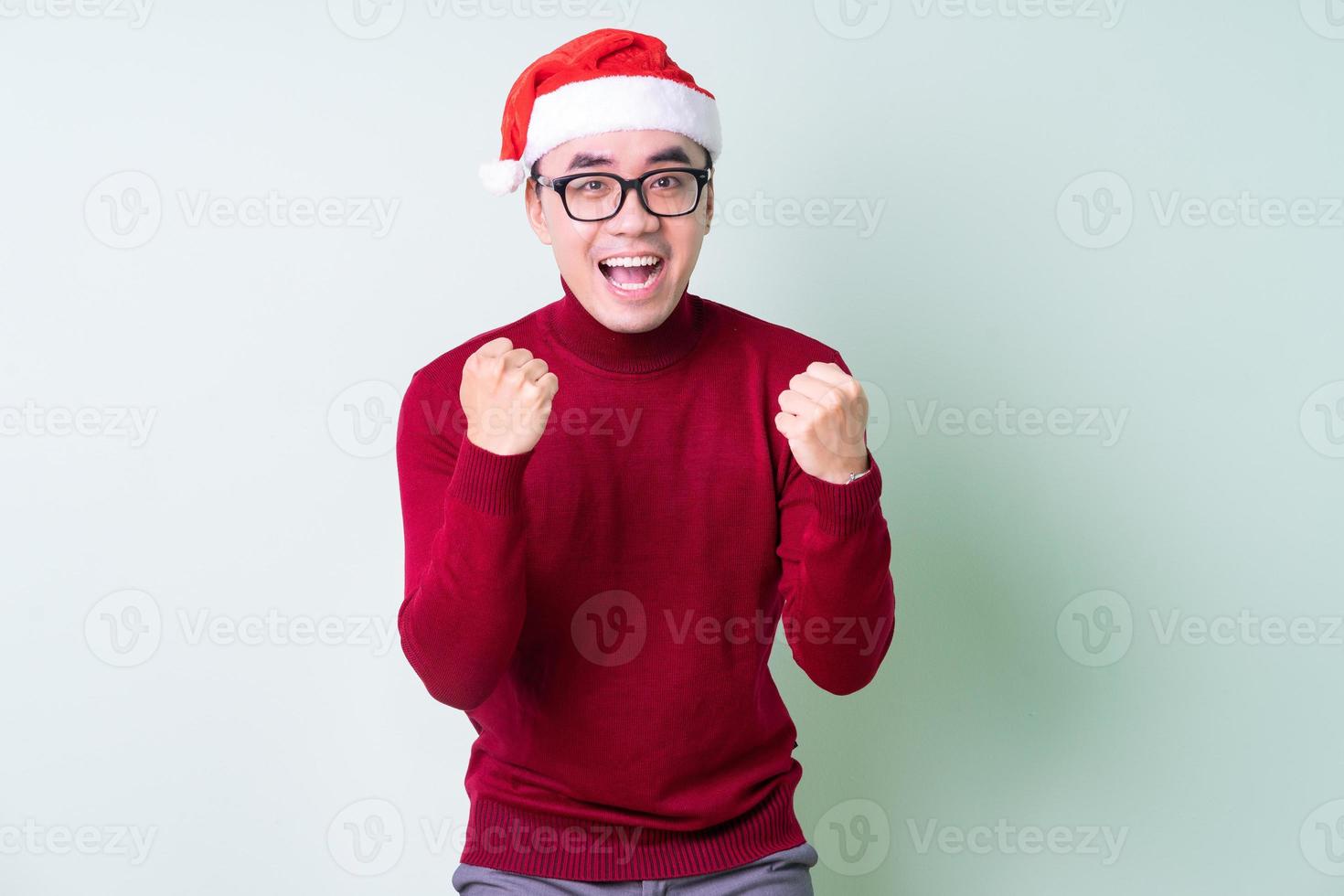 Young Asian man wearing christmas hat on green background photo