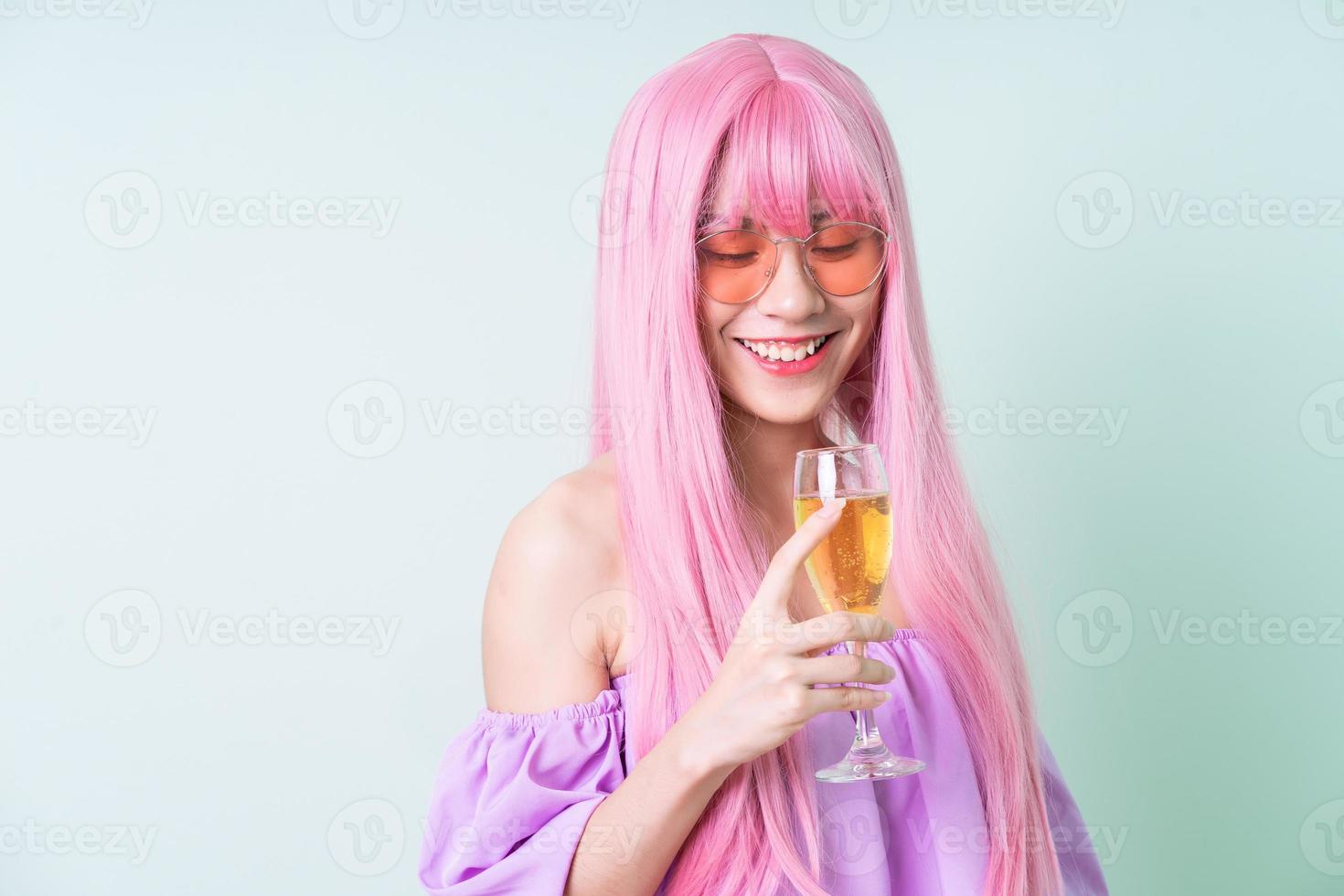 Joven mujer asiática con cabello rosado posando sobre fondo verde foto