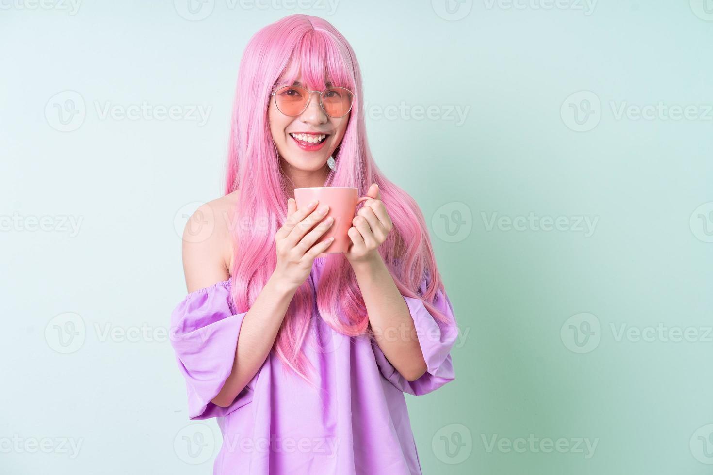 Young Asian woman with pink hair posing on green background photo