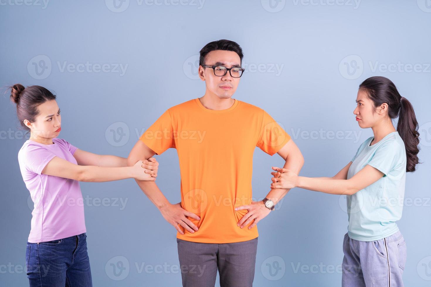 Tres jóvenes asiáticos posando sobre fondo azul. foto