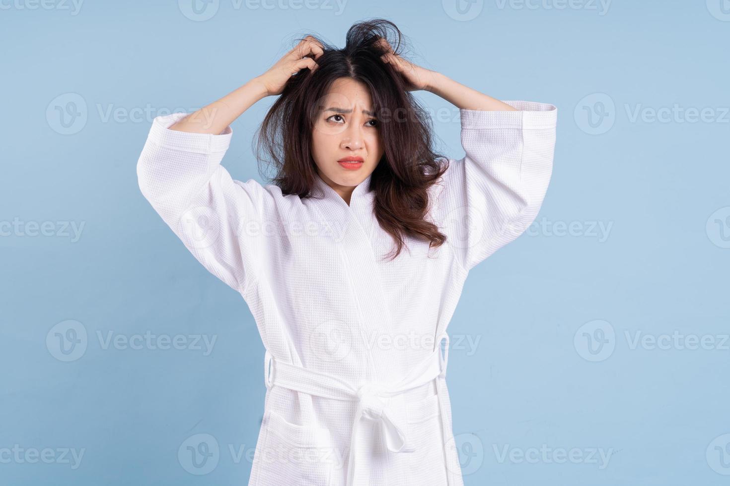 Young Asian woman wearing bathrobe on blue background photo