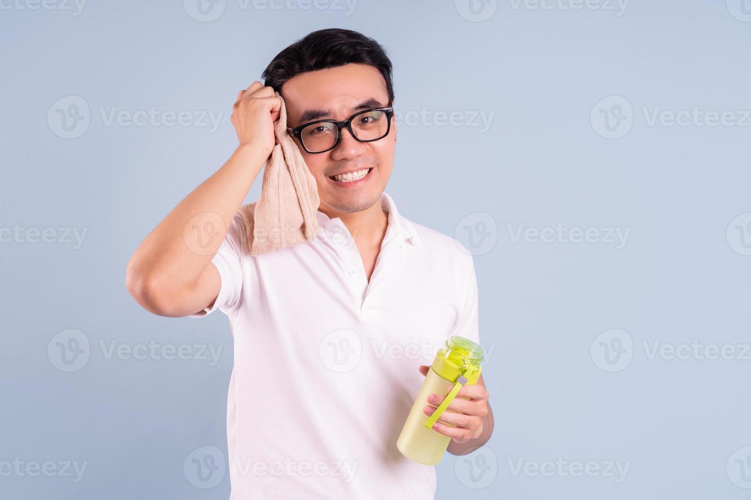 Hombre asiático vestido con ropa deportiva y sosteniendo una botella de agua, gimnasio y concepto de yoga foto