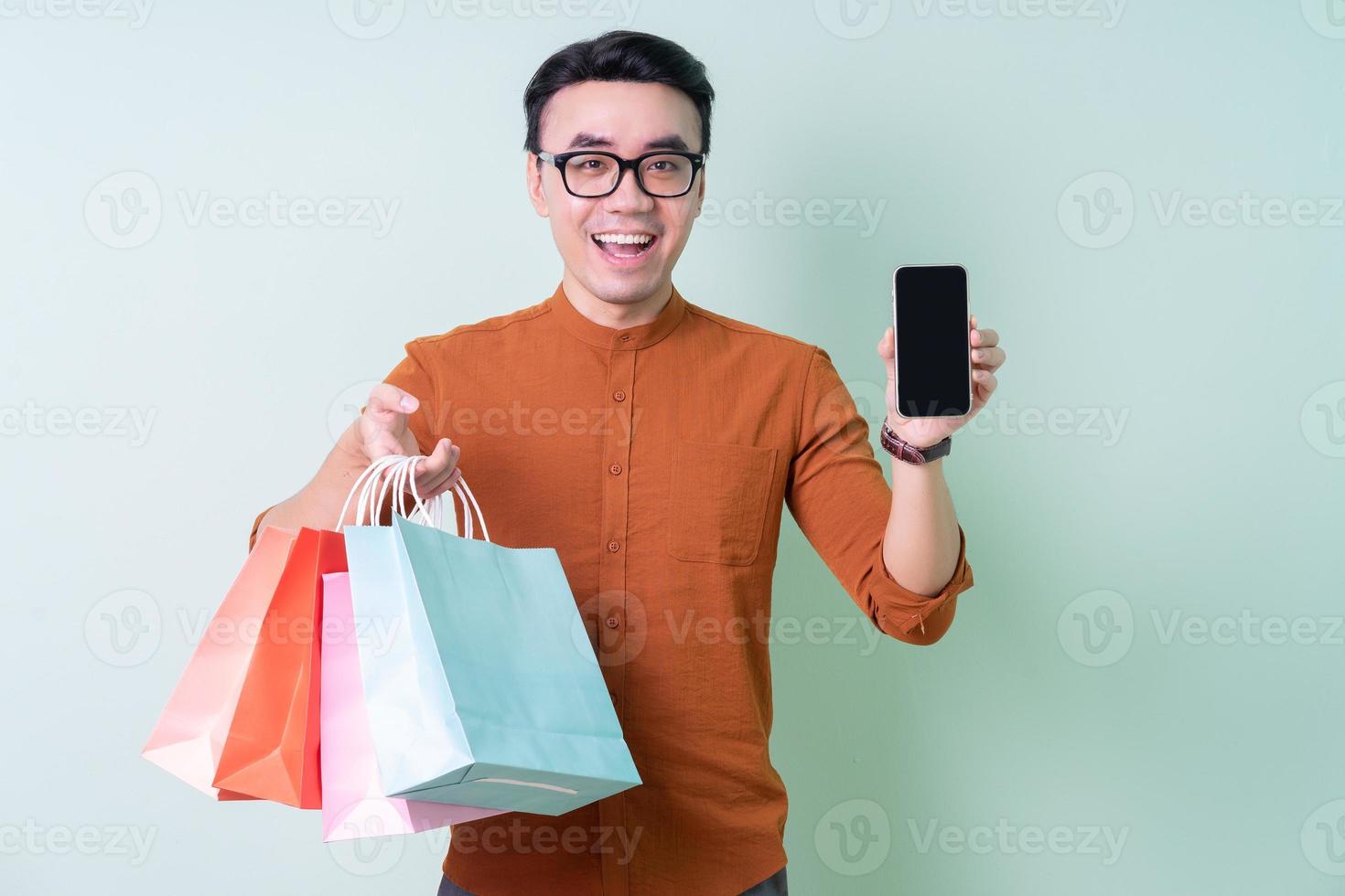 joven, hombre asiático, tenencia, bolsa de compras, en, fondo verde foto