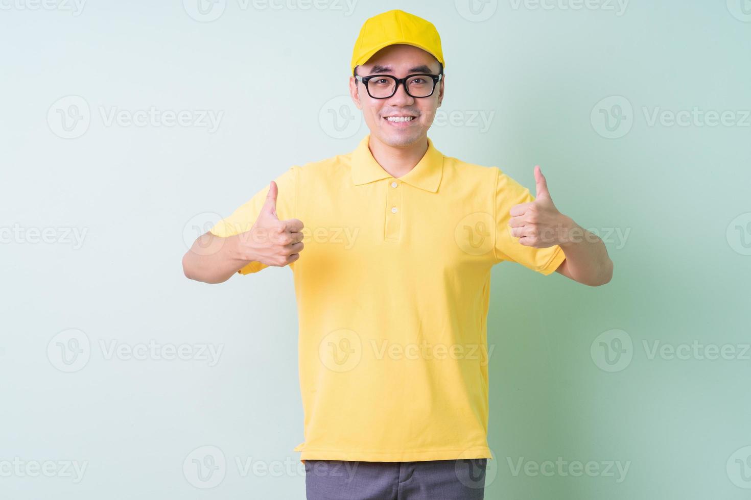 Young Asian delivery man posing on green background photo