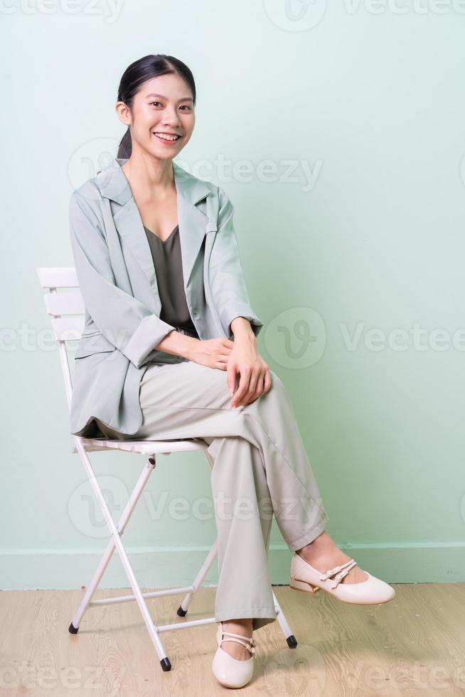 Young Asian businesswoman sitting on chair on green background photo