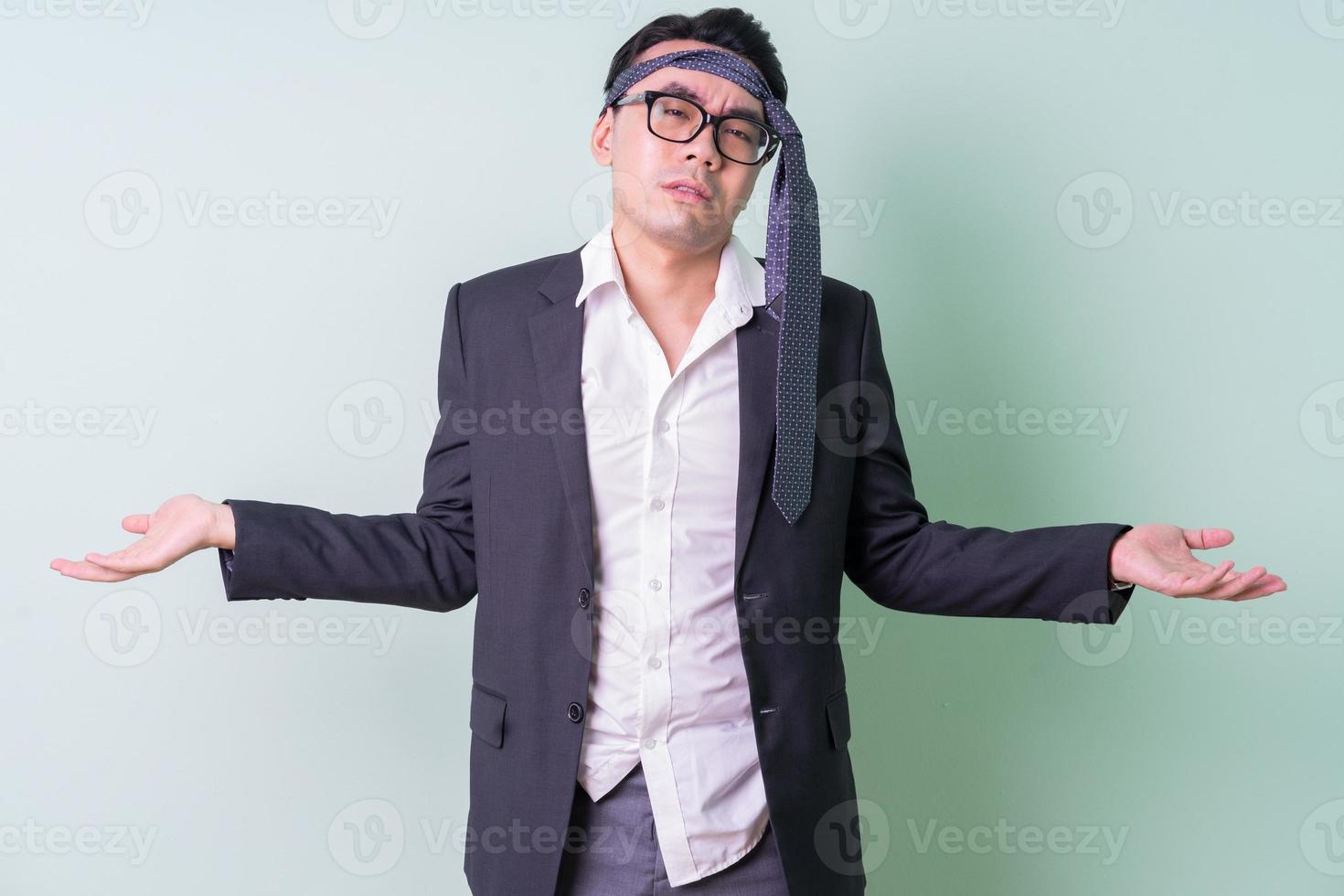 Young Asian businessman posing on green background photo