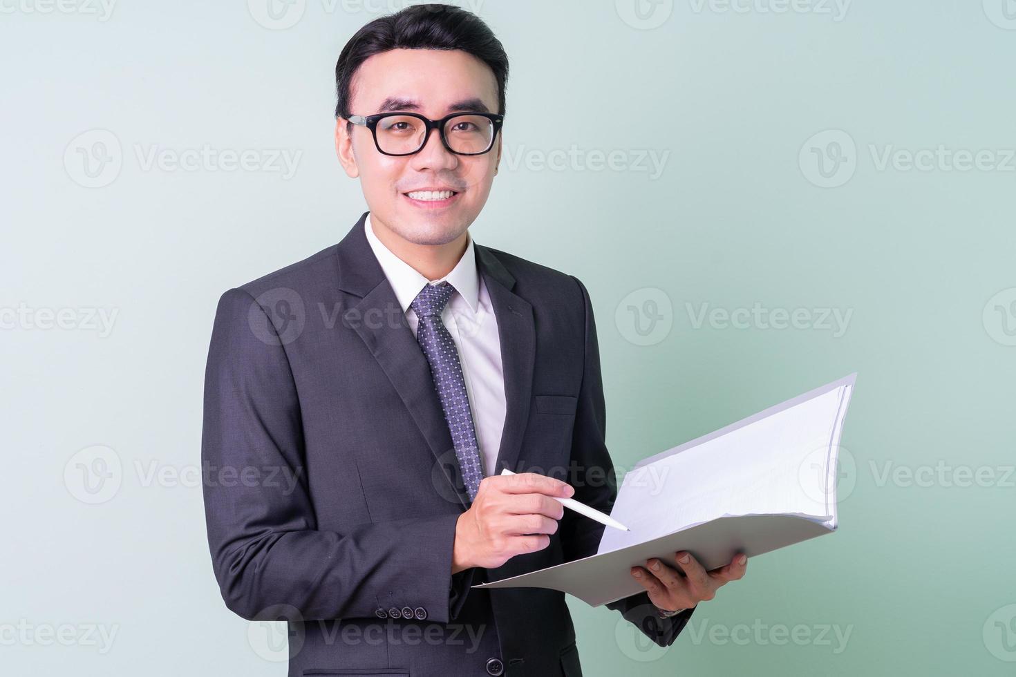 Young Asian businessman posing on green background photo