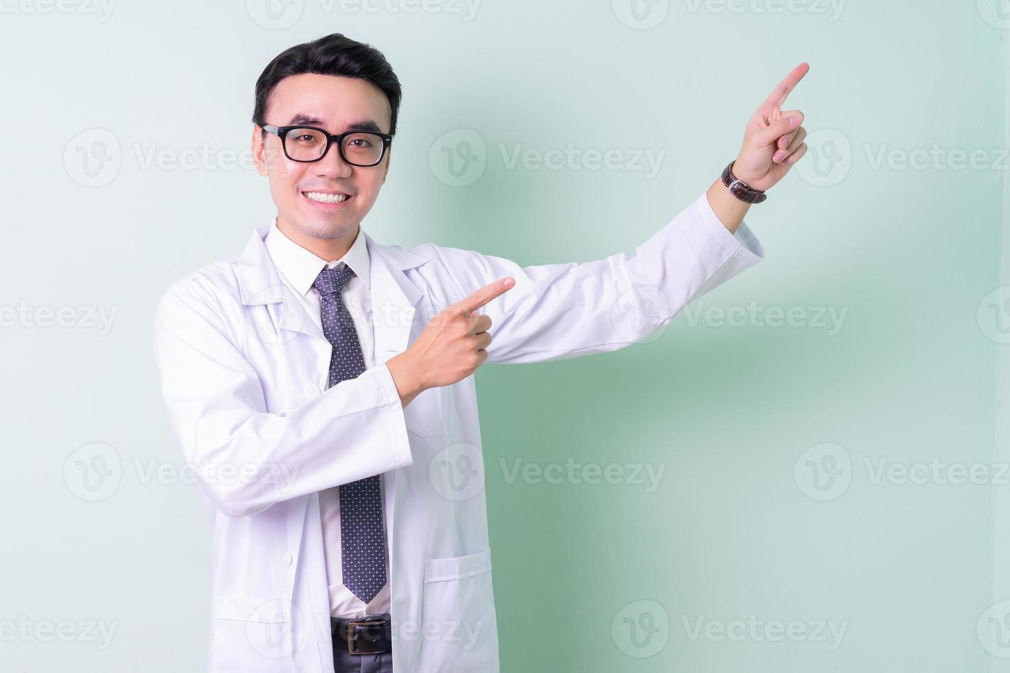 Asian doctor standing on green background photo