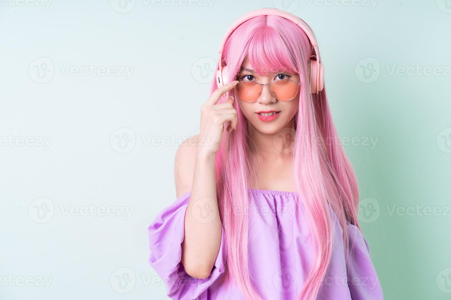 Young Asian woman with pink hair posing on green background photo