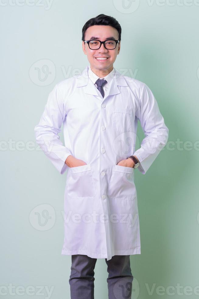 Asian doctor standing on green background photo