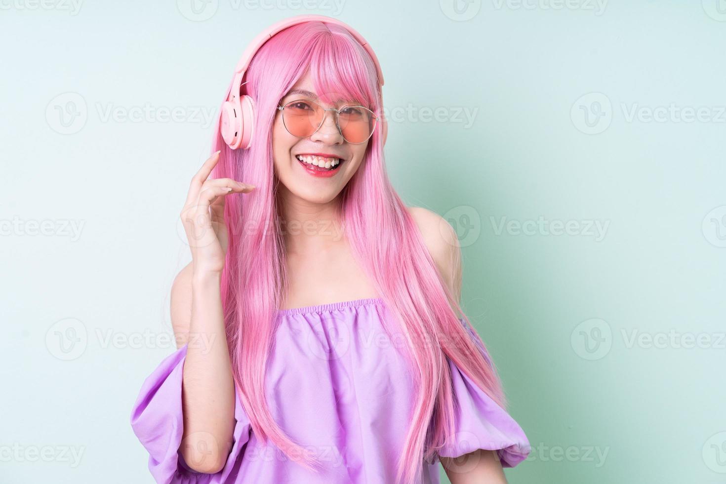 Joven mujer asiática con cabello rosado posando sobre fondo verde foto