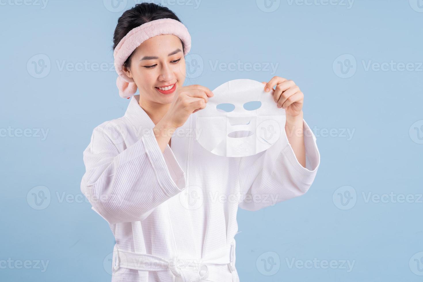 Young Asian woman wearing bathrobe on blue background photo