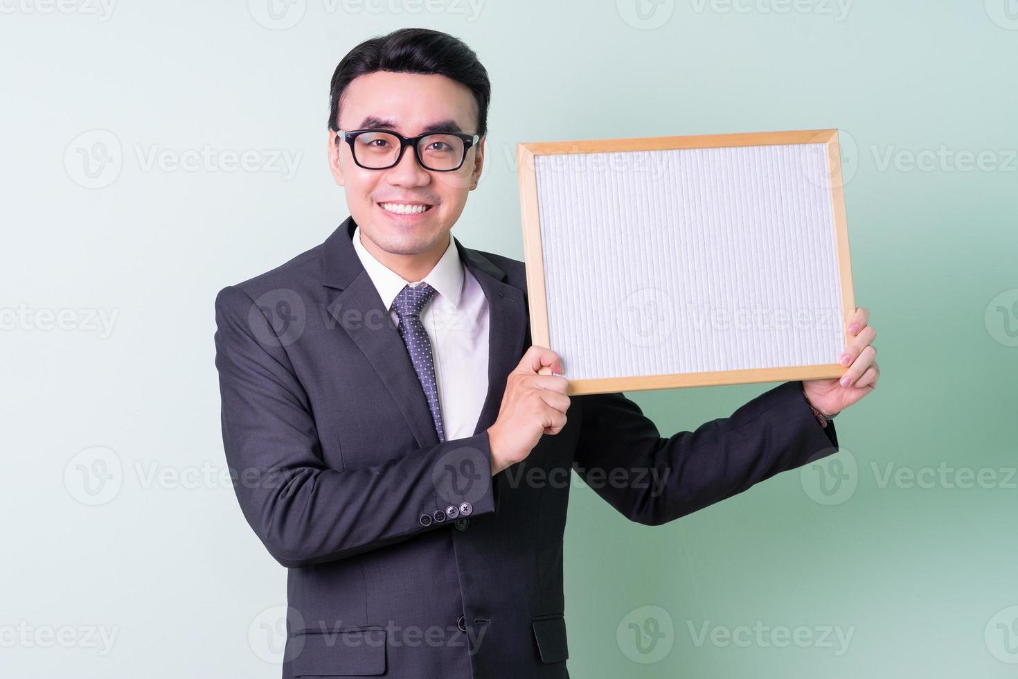 Young Asian businessman posing on green background photo