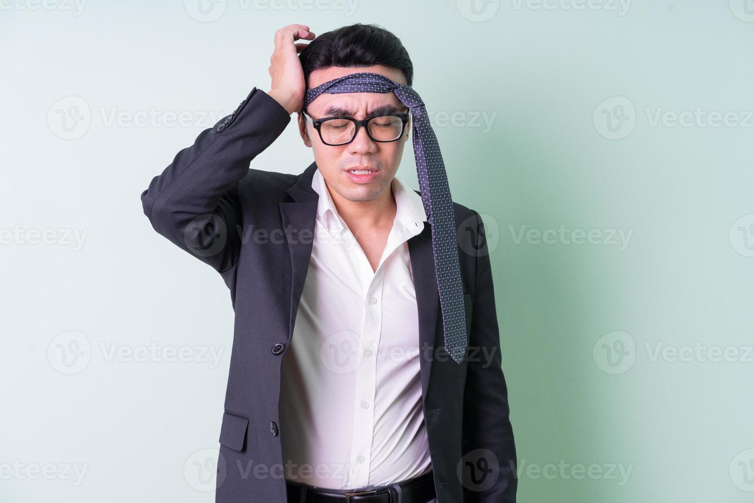 Young Asian businessman posing on green background photo
