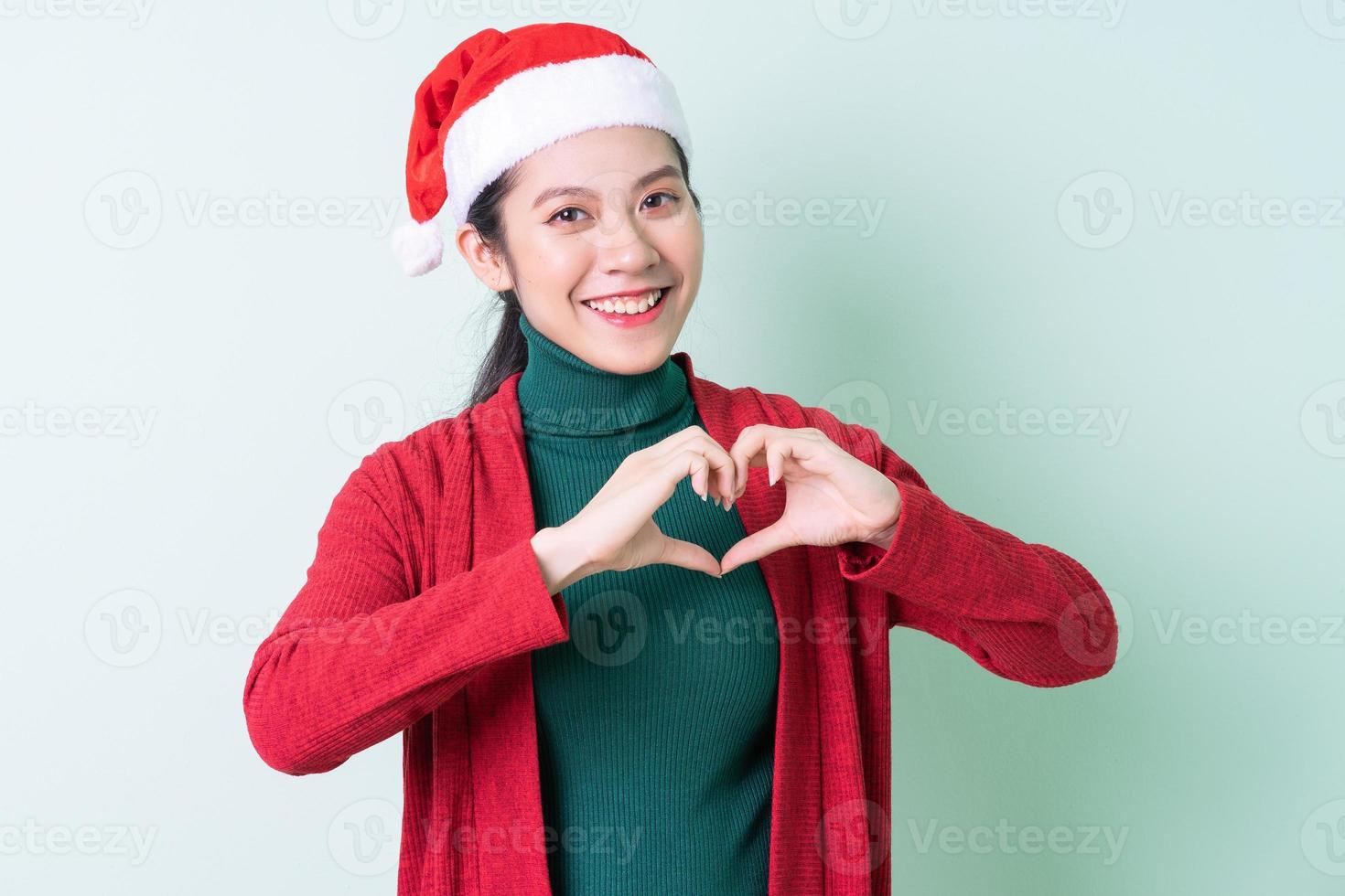 Young Asian woman wearing christmas hat on green background, x-mas concept photo