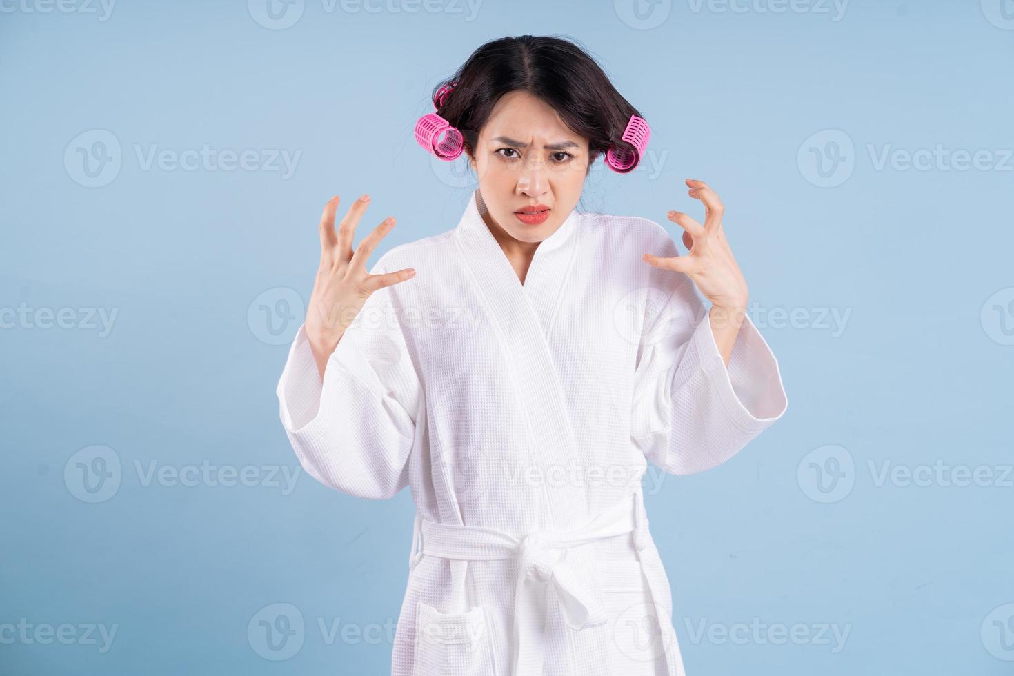 Young Asian woman wearing bathrobe on blue background photo