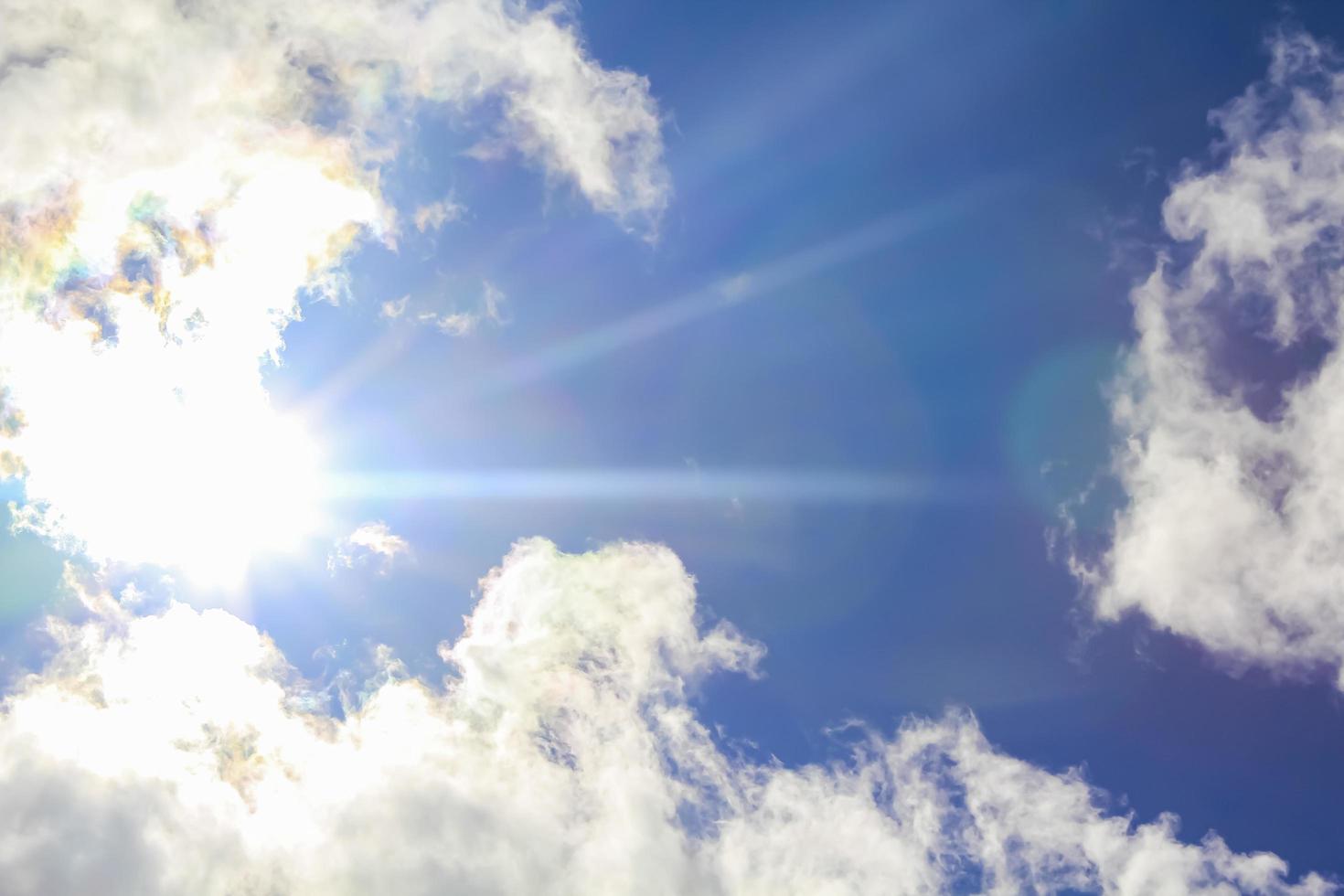 Sun rays and blue sky behind white clouds. photo