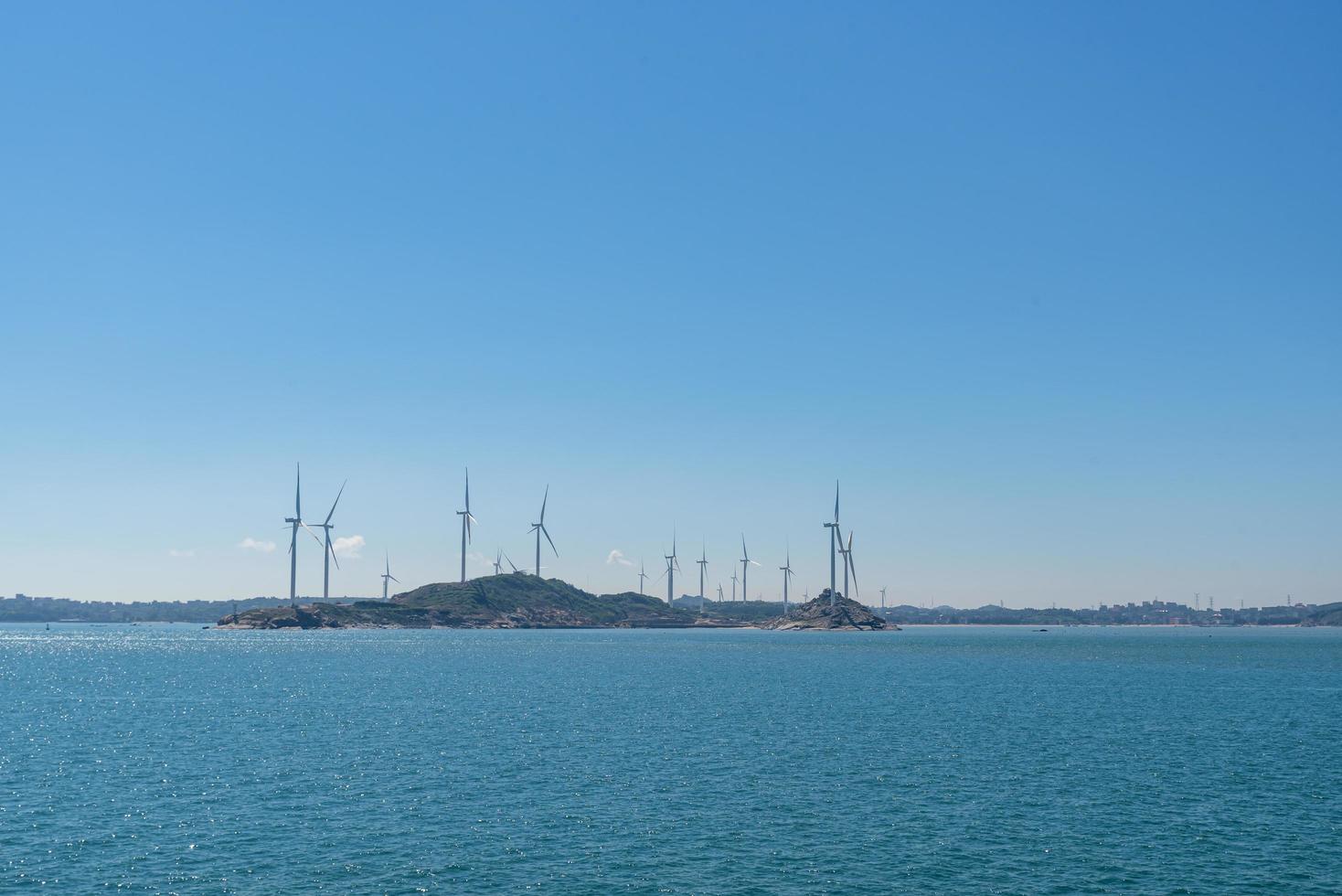 On the island in the middle of the sea, many wind turbines are installed under the blue sky photo