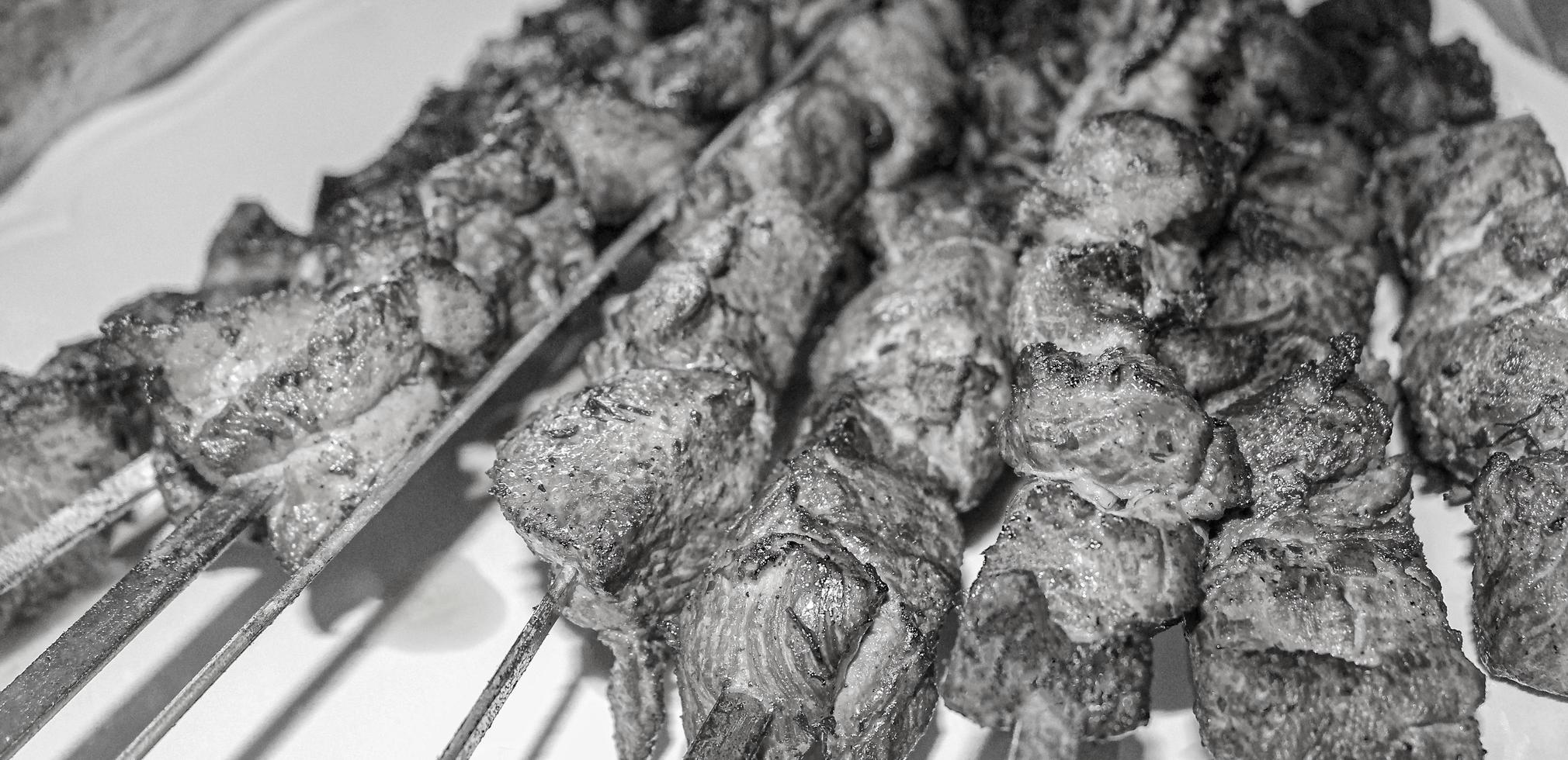 Black and white picture russian shashlik with skewers on plate. photo