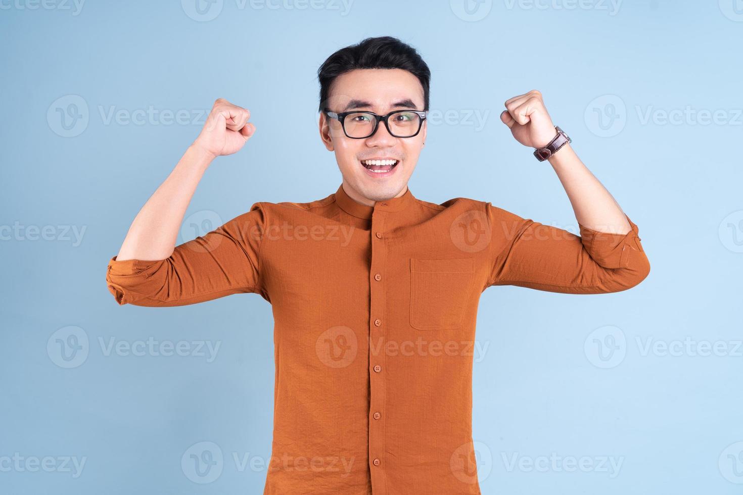 joven empresario asiático posando sobre fondo azul foto