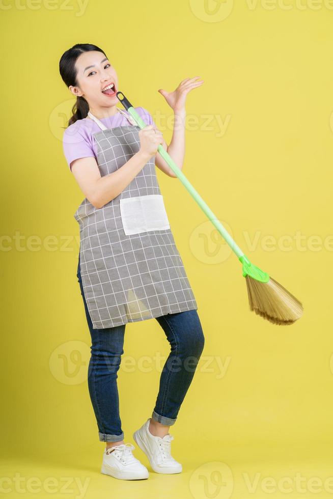 Young Asian housewife posing on yellow background photo