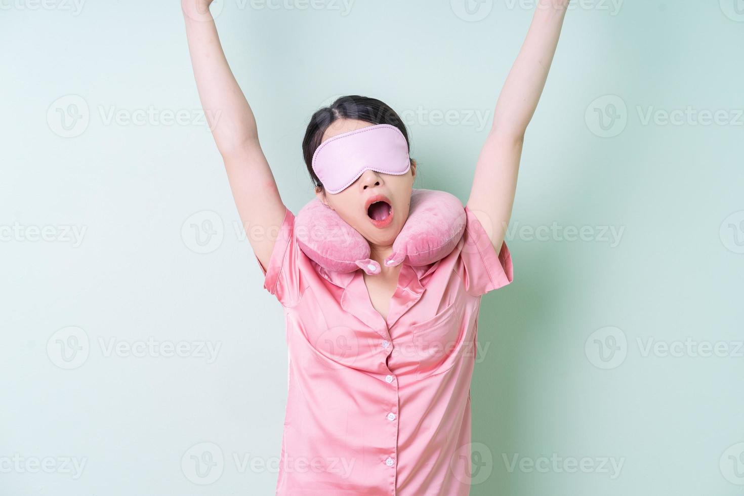 Young Asian woman wearing pajamas on green background photo