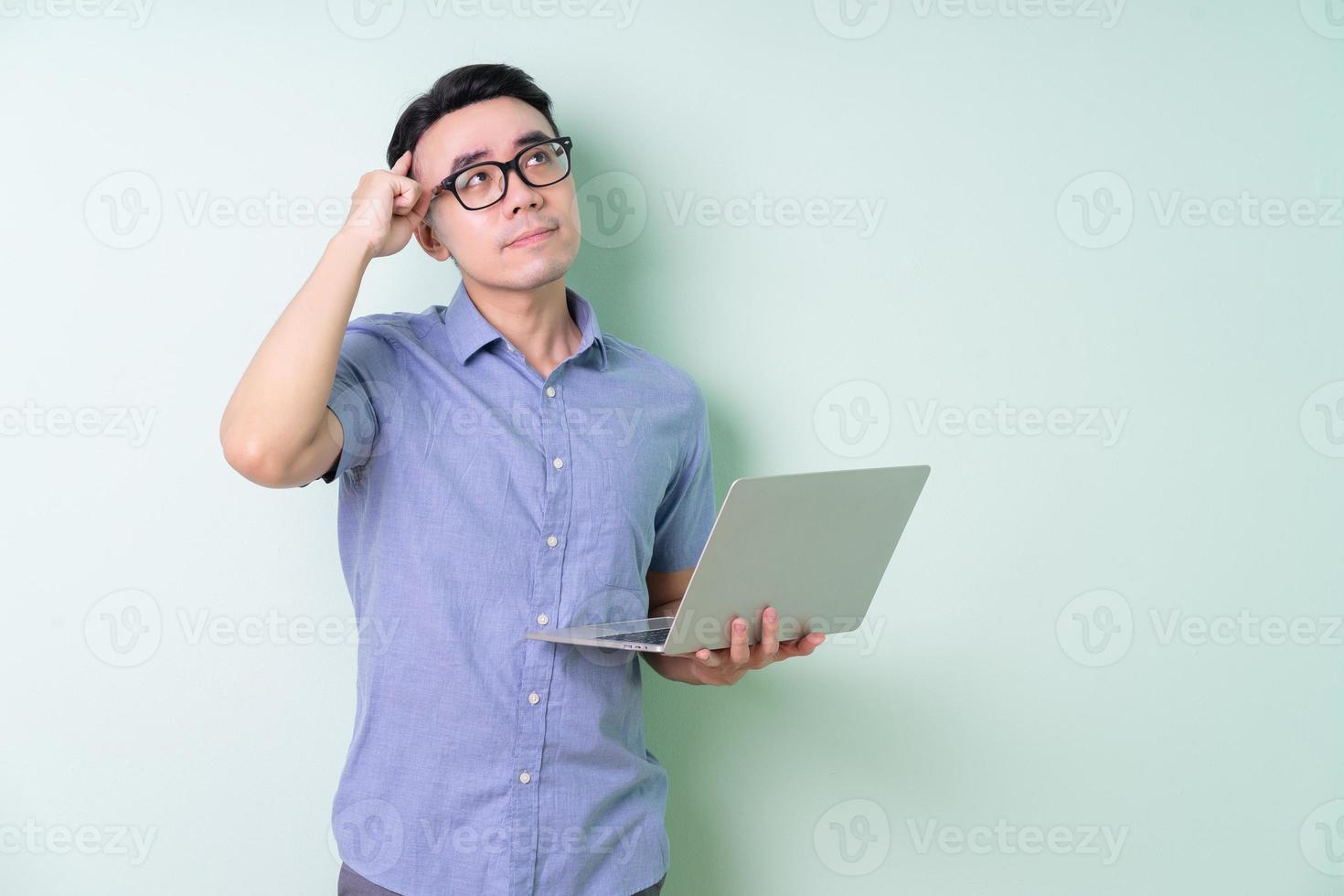 joven empresario asiático posando sobre fondo verde foto