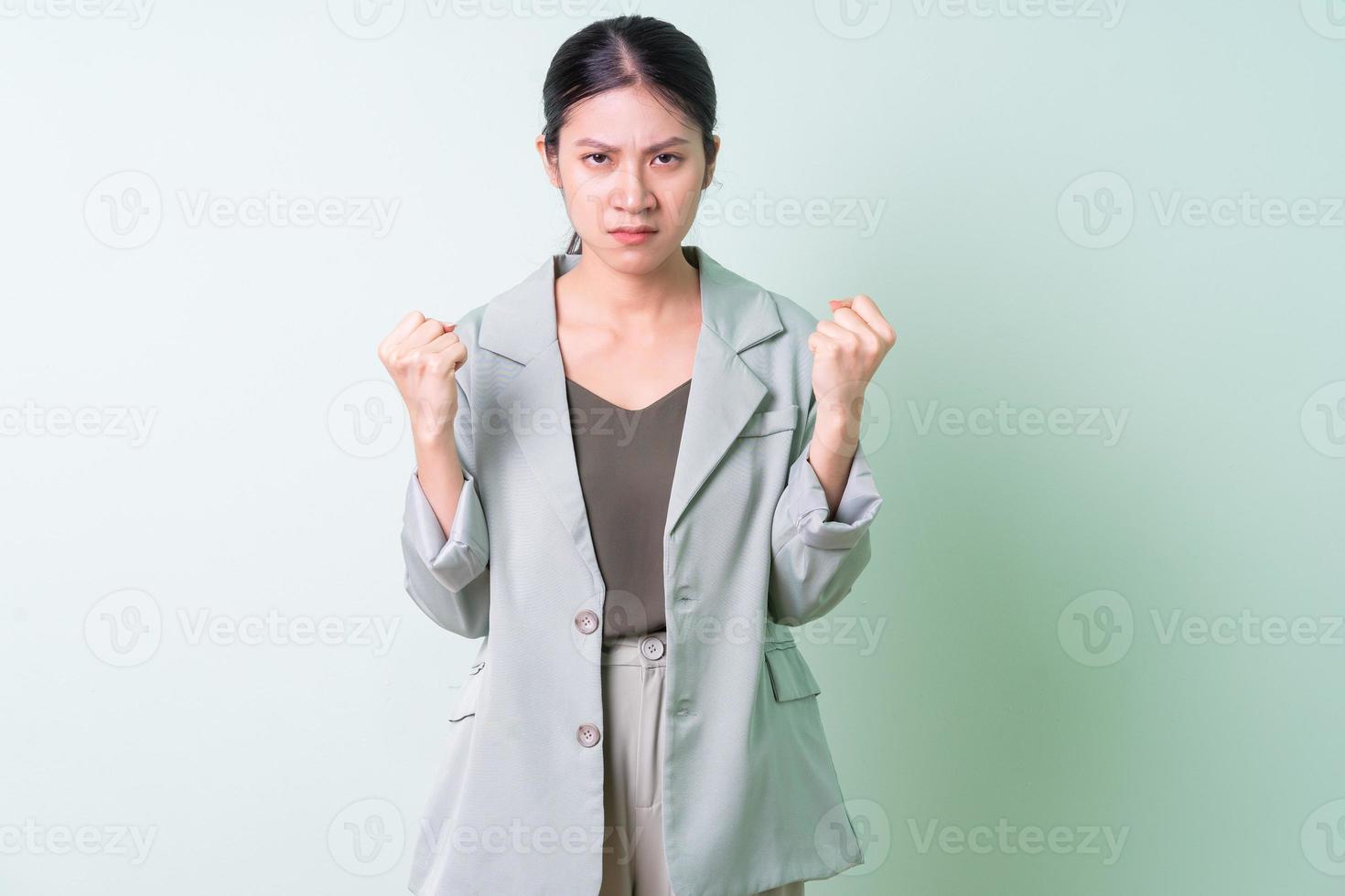 Young Asian businesswoman wearing green suit on green background photo