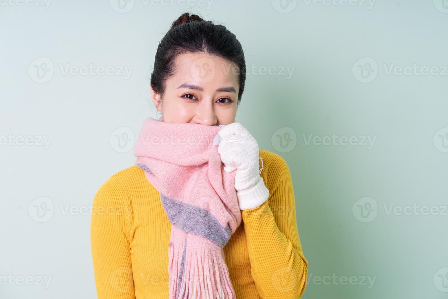 Beautiful young Asian woman wearing sweater on green background photo