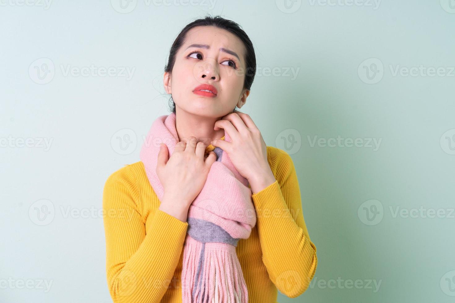 Beautiful young Asian woman wearing sweater on green background photo