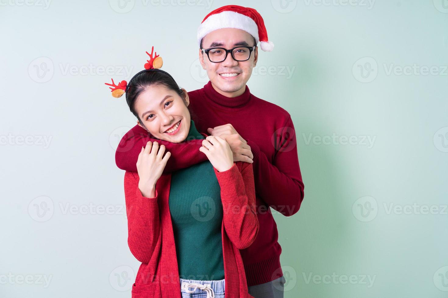 Young Asian couple posing on green background with christmas concept photo
