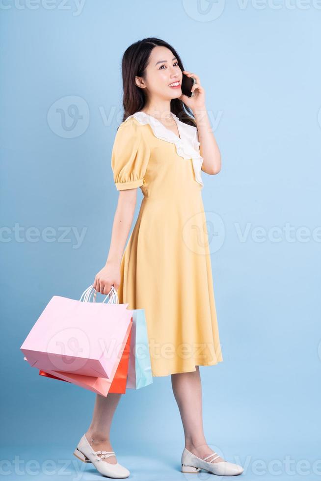 Hermosa joven asiática sosteniendo una bolsa de compras sobre fondo azul. foto