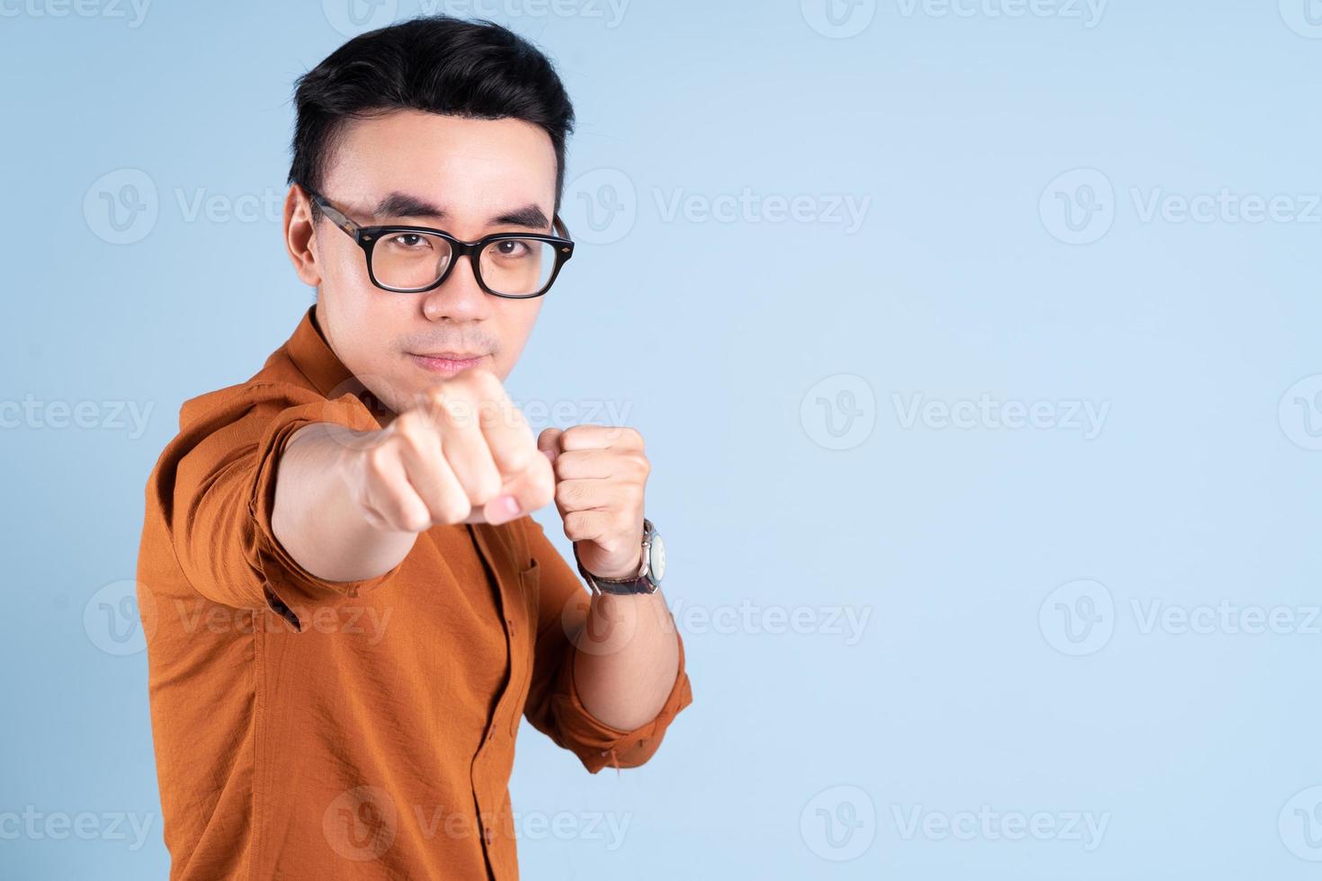 joven empresario asiático posando sobre fondo azul foto