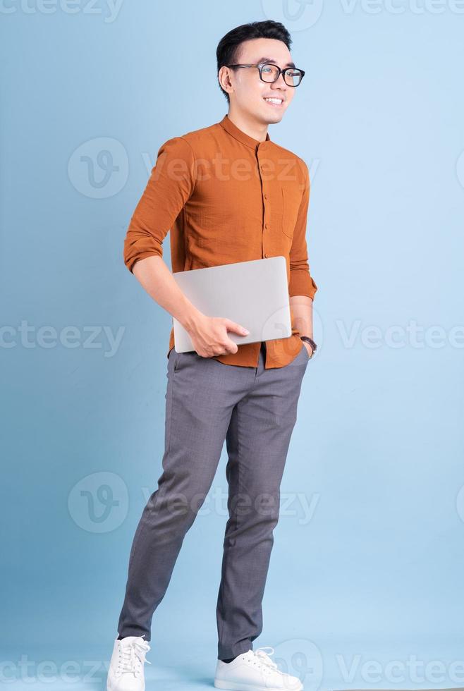 Young Asian businessman using laptop on blue background photo