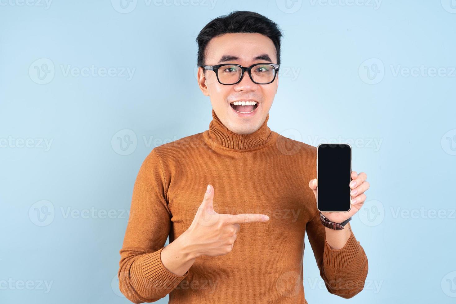 Hombre asiático con smartphone sobre fondo azul. foto