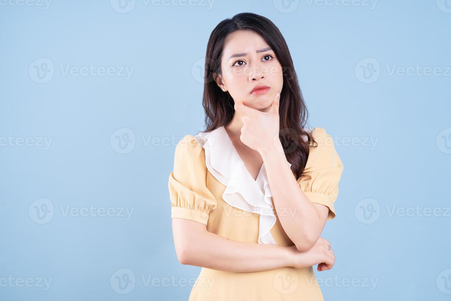 Hermosa joven asiática con vestido amarillo sobre fondo azul negro foto