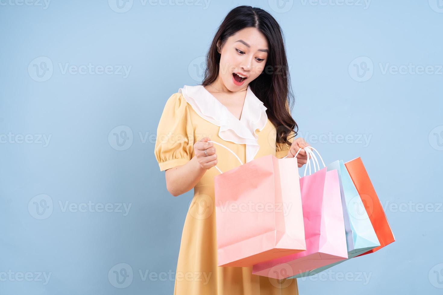 Hermosa joven asiática sosteniendo una bolsa de compras sobre fondo azul. foto