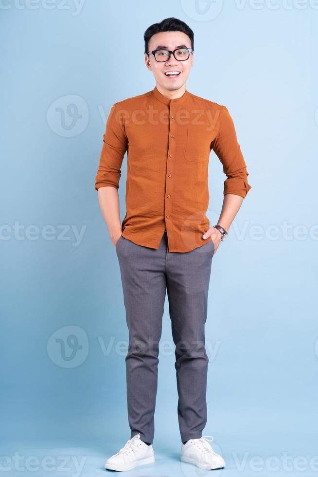 joven empresario asiático posando sobre fondo azul foto