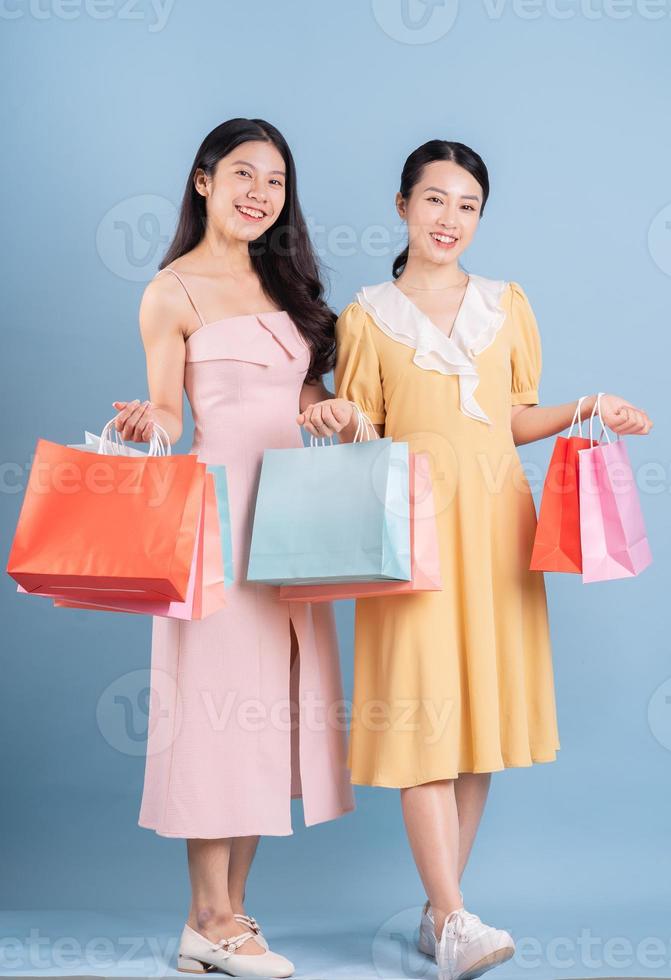 Two young Asian women holding shopping bag on blue background photo