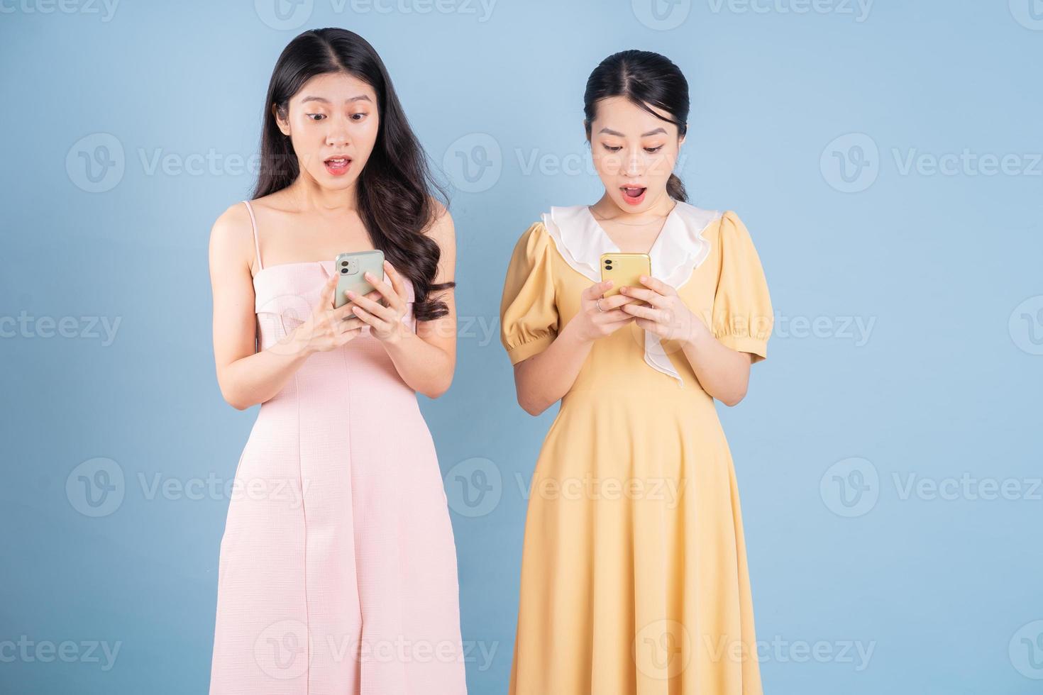 Two young Asian women wearing dress on blue background photo