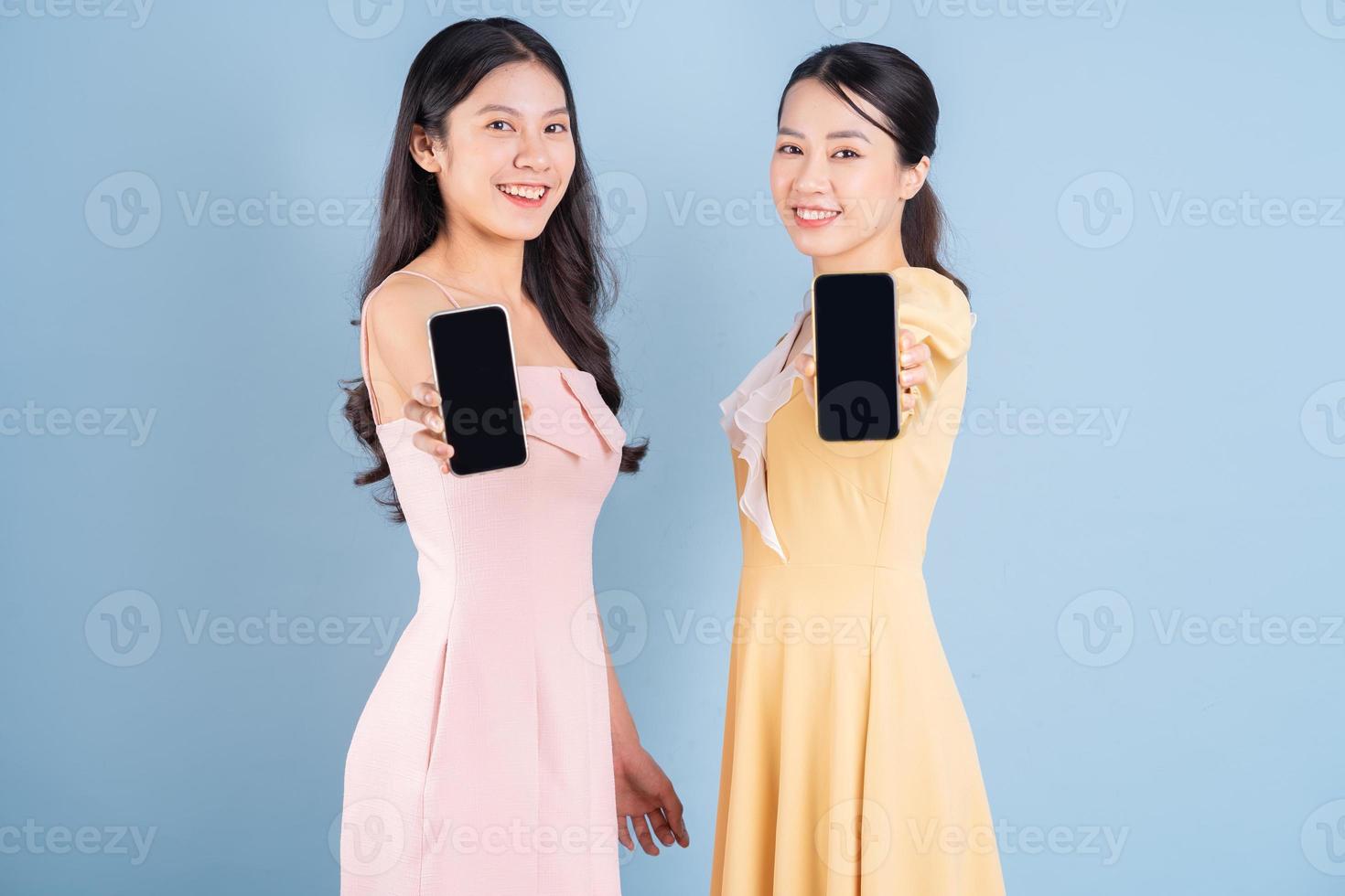 Two young Asian women wearing dress on blue background photo