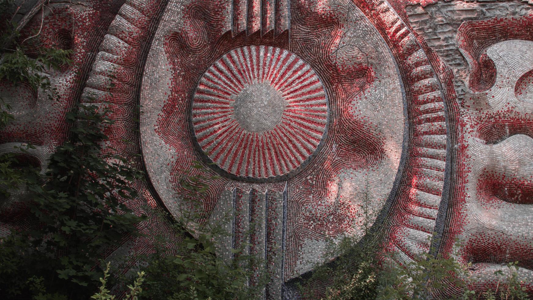 A radioactive abandoned  mosaic on the building overgrown with trees in the city of Pripyat photo