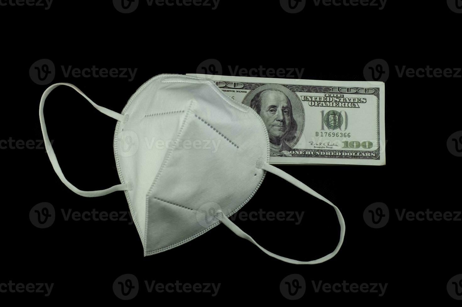 máscara de médico protección contra virus y dinero una pila de billetes de 100 dólares estadounidenses mucho en el fondo negro, es decir, cuesta un precio caro y un concepto de productos de alto precio foto