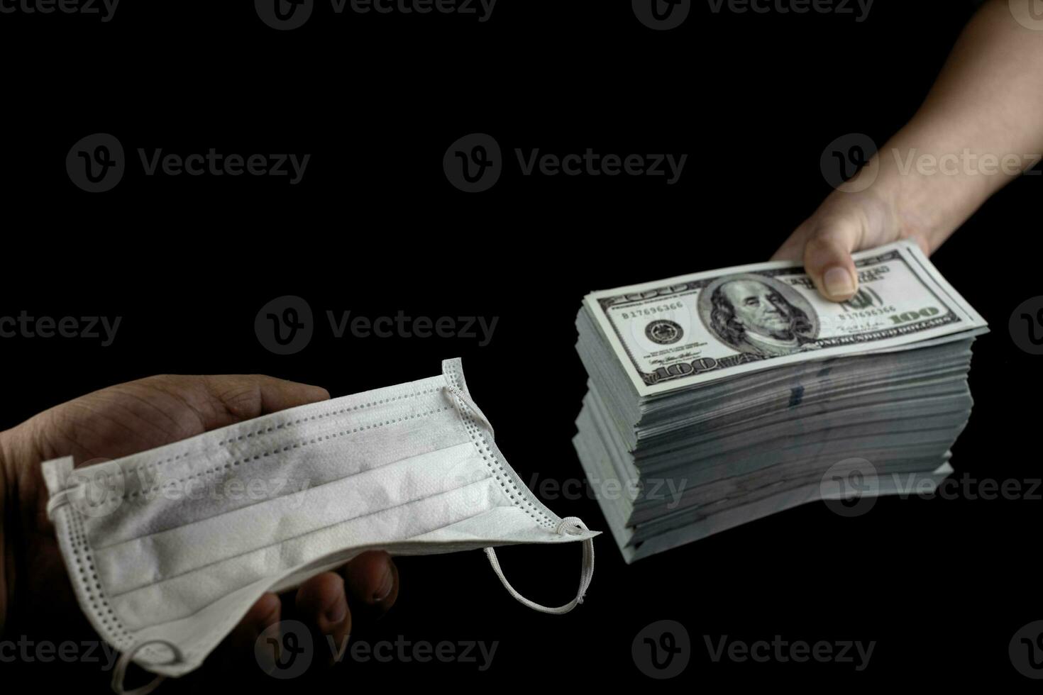 Close up Sell buy medical face mask, Hand holding doctor masks virus protection and money of 100 US dollars banknote a lot of at black background, It costs expensive and high priced products concept photo