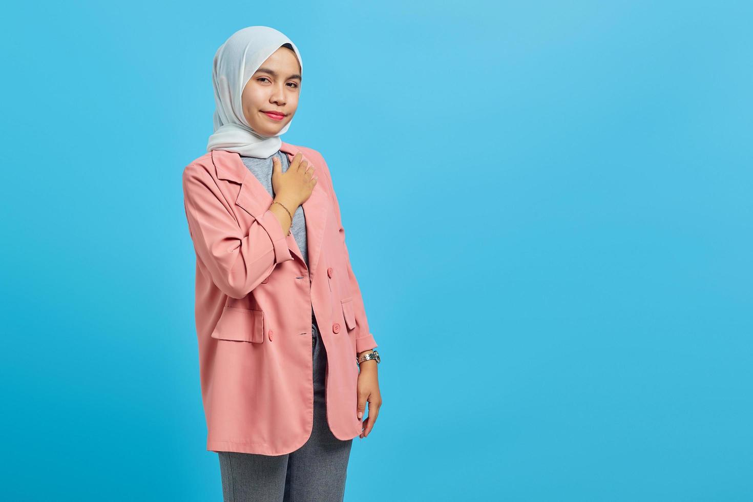 Young asian woman wearing headscarf gives greeting hands at with big smile on her face photo