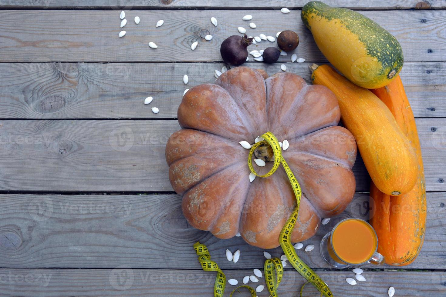 Pumpkins with zucchini on a wooden background. A glass of juice and pumpkin seeds for a diet. Natural background with pumpkins for Halloween. photo